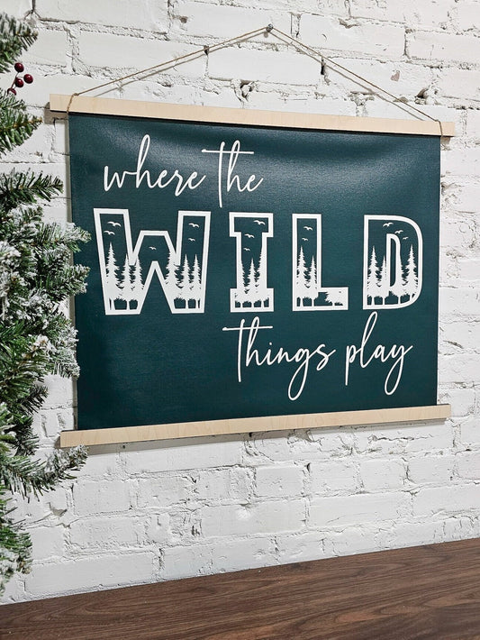 Where the wild things play, playroom hanging wall art sign, pine green background & white lettering canvas, framed top and bottom, hangs by rope, woodland letters