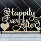 May include: Wooden sign with the text 'Happily Ever After' in cursive script. The sign has two small hearts on either side of the text. The sign is on a white wooden surface.