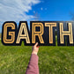 modern black/natural name sign with black backer, light colored wood name GARTH print font, all capitals
