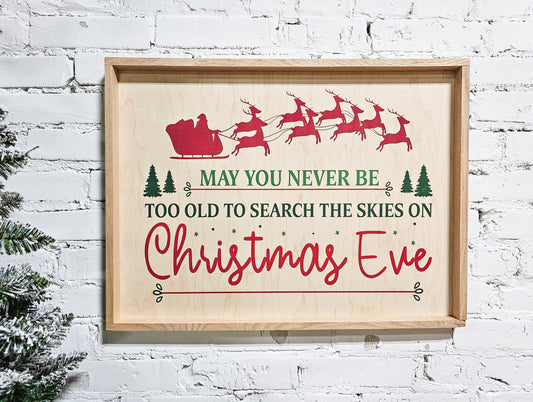 may you never be too old to search the skies on christmas eve holiday wooden sign wall decor hanging with santa claus in sleigh and reindeer at top of sign